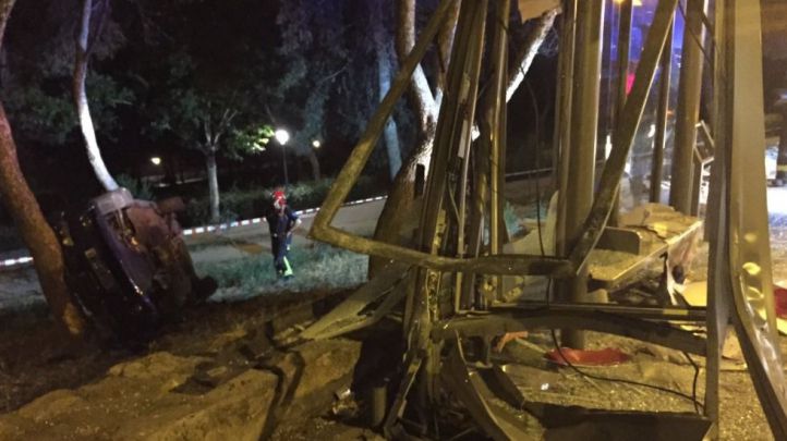 El coche pierde el control, choca contra una marquesina y vuelca en un terraplén.