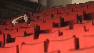 un solitario espectador entre butacas vacias de un cine o teatro