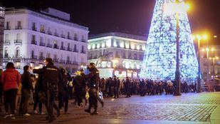 Dos jóvenes se fotografían en Sol con una pistola simulada antes de las Campanadas