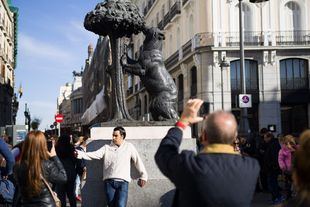 Turistas fotografiándose junto a la estatua del oso y el madroño, en la Puerta del Sol.