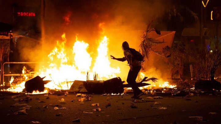 Un manifestantes corre frente al fuego durante los disturbios en la Plaza de Urquinaona, en Barcelona.