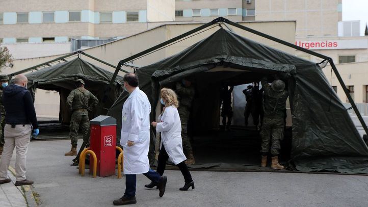 Personal sanitario pasa junto a efectivos del Mando de Ingenieros de Salamanca del Ejército de Tierra, una unidad de 34 militares, mientras instalan un hospital provisional de entre 60 y 70 camas en las inmediaciones del Hospital Gregorio Marañón