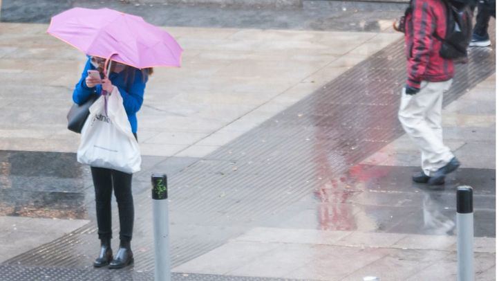 Persona con paraguas en Gran Vía, en una foto de archivo