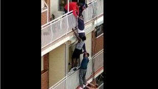 Momento en el que varios vecinos salvan a un hombre de caer al vacío