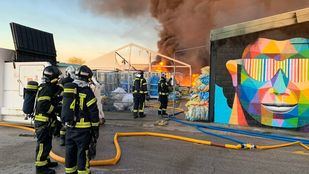 Los bomberos trabajan en la extinción de un aparatoso incendio en una nave