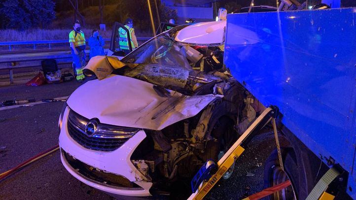 Los bomberos intentan rescatar al conductor del vehículo que se ha quedado atrapado tras la colisión