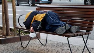 Persona sin hogar duerme sobre un banco