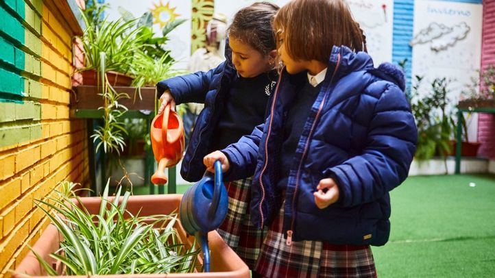 Dos alumnas del Colegio Internacional SEK Santa Isabel cuidan las plantas de su centro educativo.