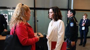 Familiares de los usuarios de la residencia de ancianos Francisco de Vitoria charlan con Ayuso en los pasillos de la Asamblea