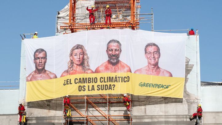 Activistas de Greenpeace han colgado hoy una pancarta en la Puerta de Alcalá con la cara de los cuatro candidatos electorales coincidiendo con la ola de calor para exigirles su compromiso con el cambio climático