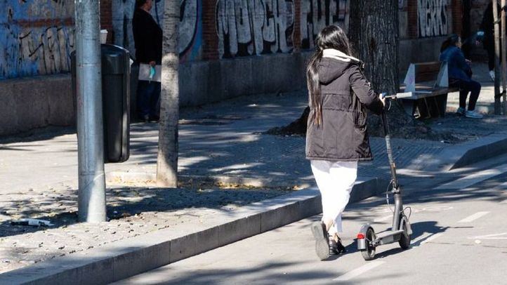 Una persona caminando con un patinete eléctrico