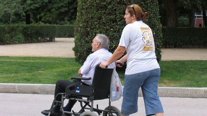 Persona mayor en silla junto a su cuidadora