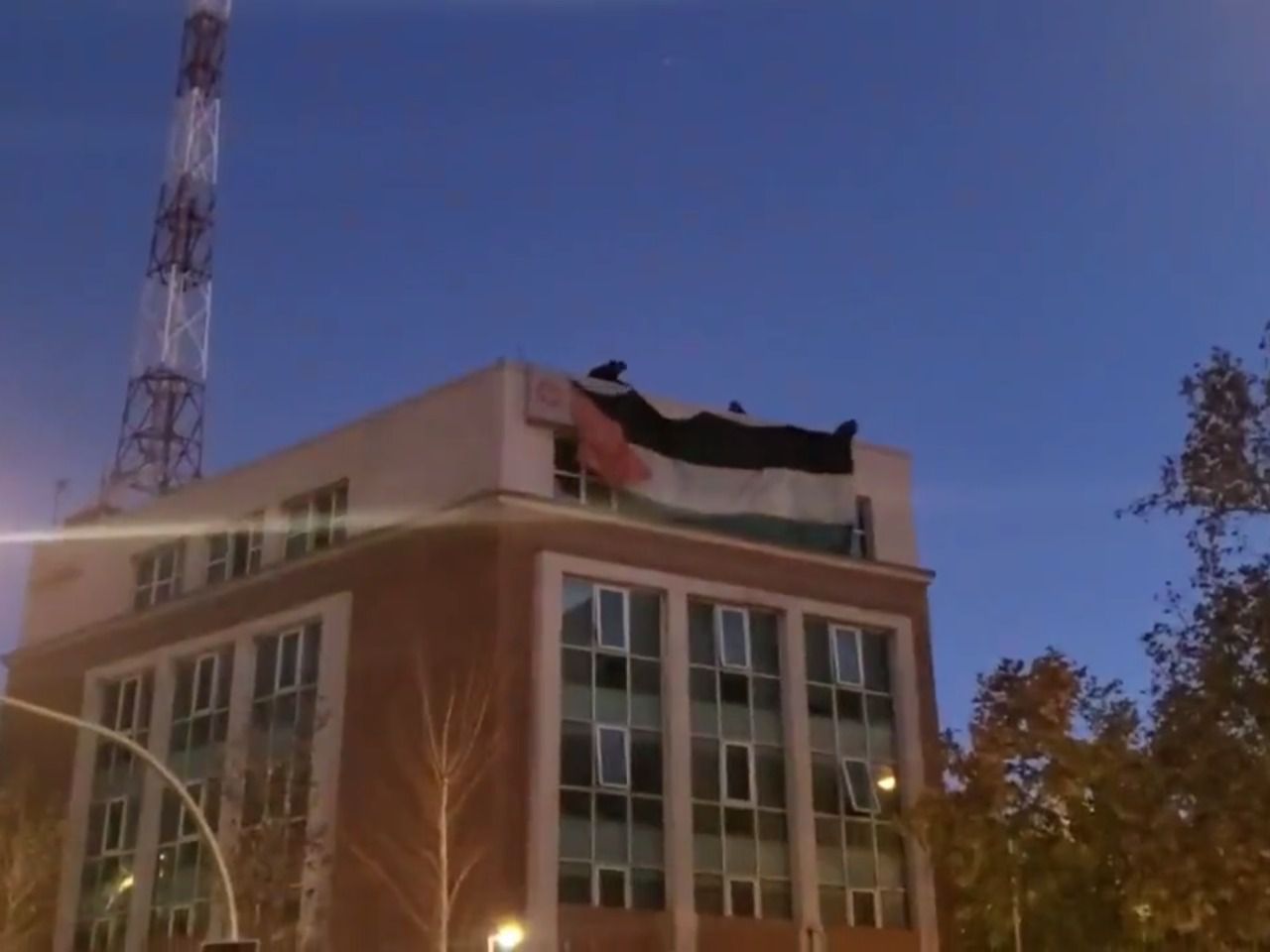 Activistas despliegan una bandera palestina y una pancarta de 'Israel