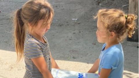Niñas cargan con un paquete de pañales en la Cañada Real