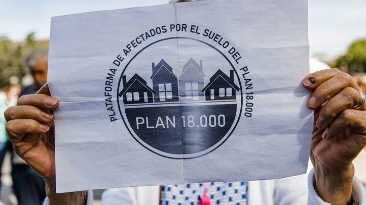 Una persona sujeta una pancarta durante una protesta sobre el Plan 18000 Venta de Suelo, frente a las puertas del Ayuntamiento, a 25 de abril de 2023