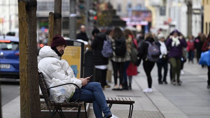 Una persona abrigada sentada en uno de los bancos de Gran Vía