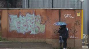 Dos migrantes se protegen de la lluvia con un paraguas en las inmediaciones del centro de Emergencia Acogida y Derivación en el Acuartelamiento 'Primo de Rivera', donde se alojan migrantes procedentes de Canarias, a 19 de enero de 2024, en Alcalá de Henares