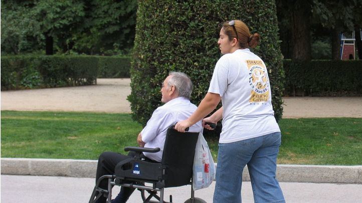 Persona mayor en silla de ruedas con su cuidadora