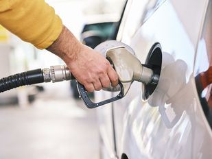 Un hombre repostando en una gasolinera.