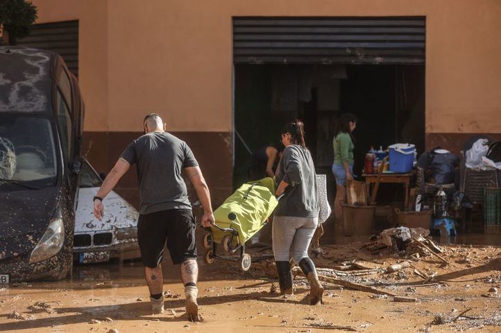 Varias personas limpian los destrozos tras el paso de la DANA en el barrio de la Torre en Valencia