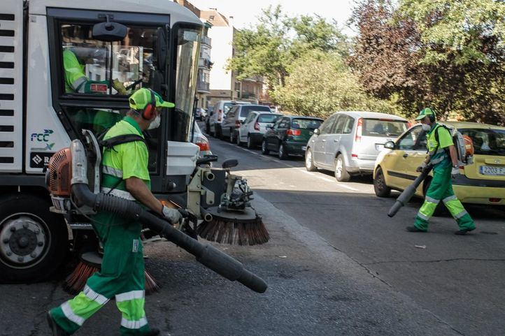 Varios barrenderos limpian con la sopladoras una calle del barrio de San Andres en Villaverde Alto.