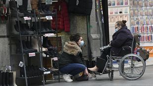 Una joven asiste a una mujer en silla de ruedas.