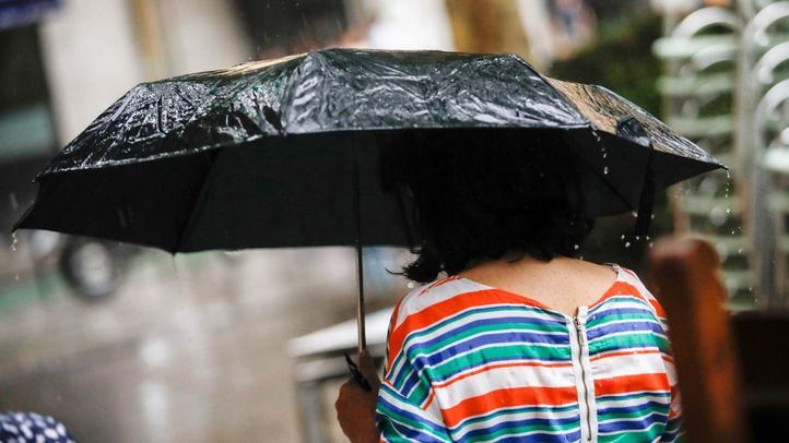 Persona resguardándose de la tormenta con su paraguas, en una imagen de archivo