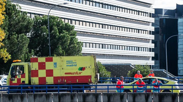Varias personas del Servicio de Limpieza Urgente (SELUR) observan un helicóptero tras un accidente en la carretera M-40