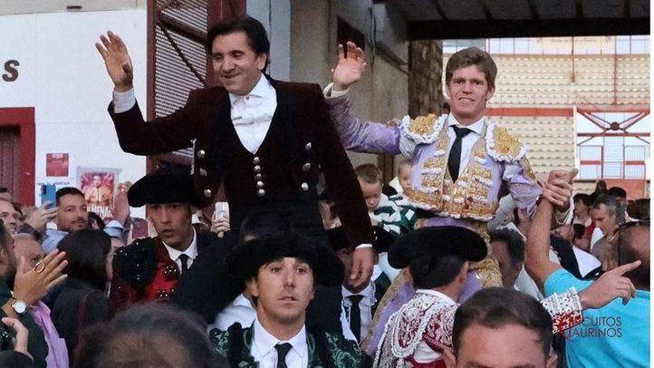 El rejoneador, a la izquierda, y el matador a pie saludan al ser sacados a hombros de la plaza.