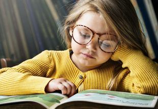 Niña con gafas leyendo un cuento