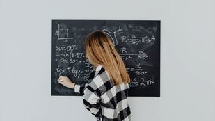 Una estudiante resuelve problemas de matemáticas en una pizarra