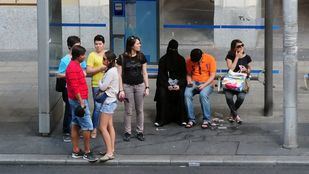Una mujer espera un autobús enfundada en un niqab
