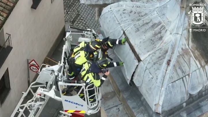 Bomberos sujetan una plancha desprendida de la Basílica de San Miguel en Madrid