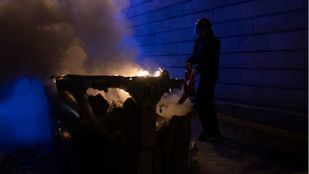 Imagen de archivo de un Policía tratando de apagar un contenedor incendiado