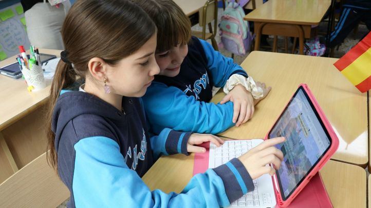 Estudiantes del centro educativo en un aula con un dispositivo tecnológico.
