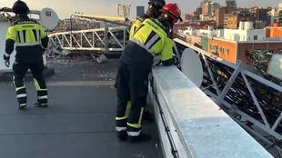 Bomberos de Madrid retiran una antena de telefonía que ha caído sobre la cubierta de un edificio.