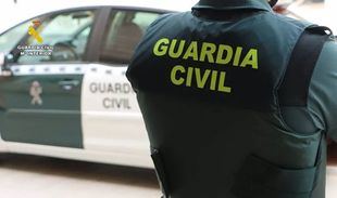 Un agente de la Guardia Civil junto a un vehículo oficial.