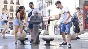 Viandantes se refrescan en una fuente