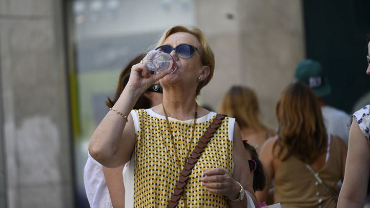 Una mujer bebiendo agua para combatir el calor.