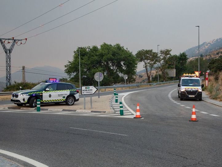 Vehículos de la guardia civil vigilan la carretera cortada durante las labores de extinción del incendio forestal, a 25 de julio de 2026, en Robledo de Chavela, Madrid