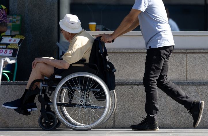 Una persona en silla de ruedas con un asistente persona