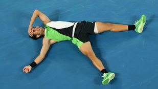 Carlos Alcaraz, tendido en la pista del Melbourne Park, tras derrotar a Novak Djokovic