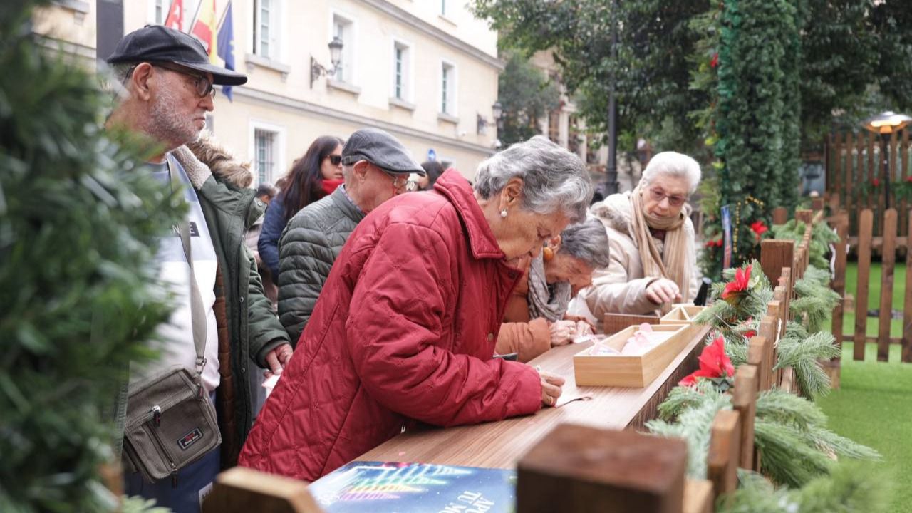 Los usuarios del SAD de Atende escriben sus mensajes de Navidad para colgar en el Árbol de los Deseos de la Plaza de Pontejos.